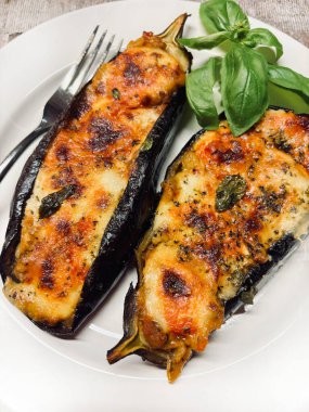 Mozarella peynirli ev yapımı patlıcan, doğranmış domates ve beyaz tabakta taze fesleğen yaprağı. Vejetaryen yemeği. Tam üstte.