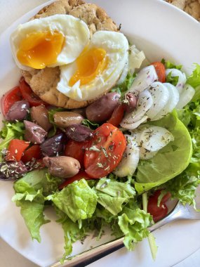 Beyaz tabakta servis edilen haşlanmış yumurtalarla birlikte taze ve sağlıklı sebze salatası. Sağlıklı gıda konsepti. Tam üstte.