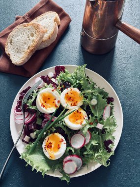 Beyaz tabakta servis edilen haşlanmış yumurtalı taze sağlıklı sebze salatası, yeşil arka plan. Tam üstte.