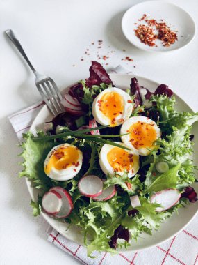 Beyaz tabakta servis edilen haşlanmış yumurtalarla birlikte taze ve sağlıklı sebze salatası. Sağlıklı gıda konsepti. Tam üstte.