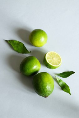 Gri ışıklı arka planda yaprakları olan bir grup taze limon meyvesi. Sağlıklı gıda konsepti. Uzayı kopyala Tam üstte.