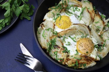 Koyu arkaplanda demir bir tavada ev yapımı yumurta ve rezene. Sağlıklı ve vejetaryen yemekleri. Tam üstte.