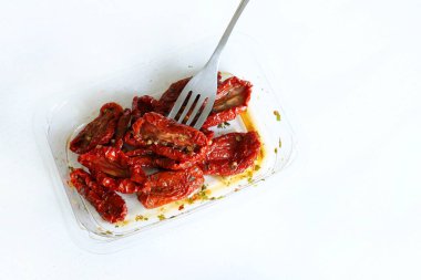 Beyaz ahşap bir masada izole edilmiş bir grup kuru domates. Zeytinyağı ve bitkilerle kurutulmuş domates dilimleri. İtalyan yemeği..