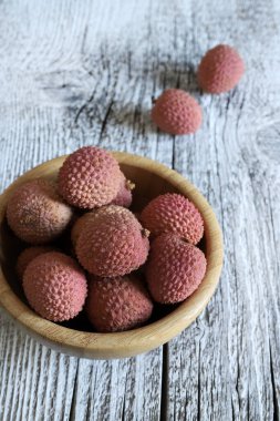 Taze kırmızı Lychee, ya da ahşap bir arka planda izole edilmiş bambu kasesinin üzerindeki Litchi. Sağlıklı ve vejetaryen yemekleri.