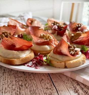 Beyaz tabakta Gorgonzola, benek ve ceviz ile nefis mezeler. Tam üstte.