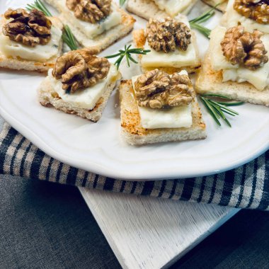 Gorgonzola ile nefis mezeler, gri arka planda beyaz bir tabakta ceviz ve bal. İtalyan yemeği. Tam üstte.