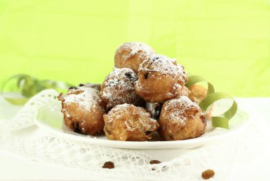 Traditional Italian carnival sweets. Homemade carnival fritters with sultanas sprinkled with icing sugar on green background.  clipart