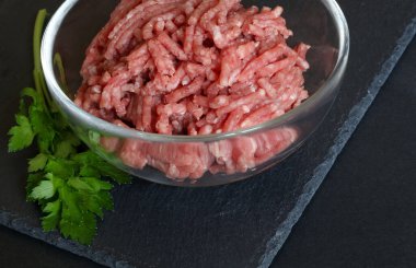 Siyah arka planda izole edilmiş cam bir kasede taze kıyma. Yakın plan..