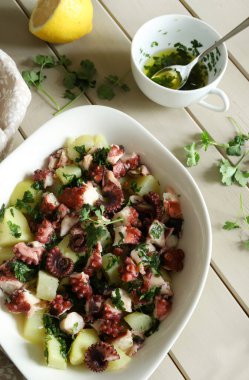 İtalyan ahtapot ve maydanozlu patates salatası ve ahşap masada limon. Sağlıklı yiyecekler. Deniz ürünleri salatası. Tam üstte.