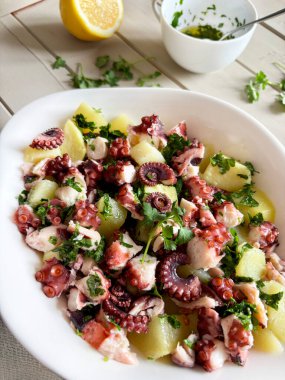 İtalyan ahtapot ve maydanozlu patates salatası ve ahşap masada limon. Sağlıklı yiyecekler. Deniz ürünleri salatası. Tam üstte.
