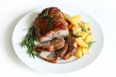 Dilimlenmiş hindi yahnisi manzarası. Beyaz bir tabakta kızarmış hindi, patates ve beyaz ahşap bir masada biberiye..