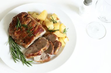 Dilimlenmiş hindi yahnisi manzarası. Beyaz bir tabakta kızarmış hindi, patates ve beyaz ahşap bir masada biberiye..