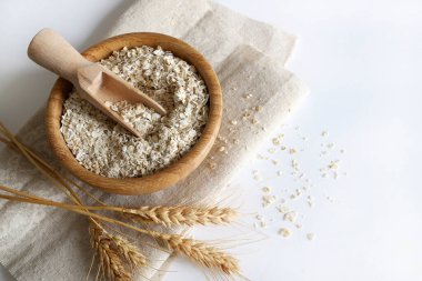 Yuvarlanmış yulaf. Tahta bir kasede beyaz arka planda tahıl gevreği. Sağlıklı kahvaltı, sağlıklı beslenme. Tam üstte, boşluğu kopyala.