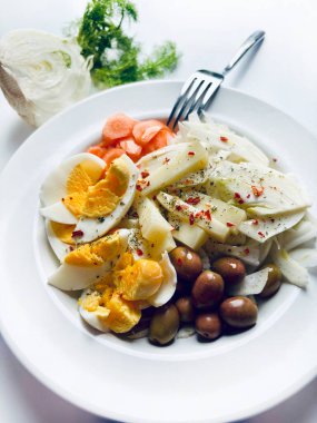 Yumurta ve taze sebzeli rezene salatası, beyaz arka planda izole edilmiş havuç zeytinleri. Sağlıklı yiyecekler. Tam üstte.