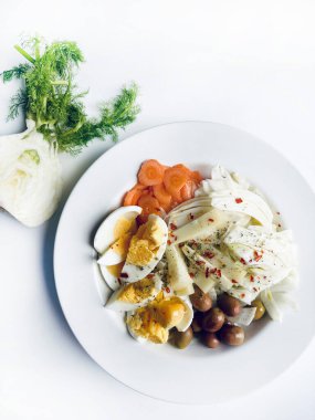 Yumurta ve taze sebzeli rezene salatası, beyaz arka planda izole edilmiş havuç zeytinleri. Sağlıklı yiyecekler. Tam üstte.