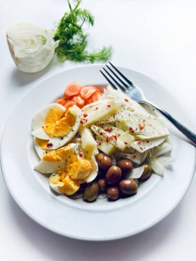 Yumurta ve taze sebzeli rezene salatası, beyaz arka planda izole edilmiş havuç zeytinleri. Sağlıklı yiyecekler. Tam üstte.