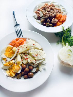 Yumurtalı, ton balıklı ve taze sebzeli rezene salatası, beyaz arka planda izole edilmiş havuç zeytinleri. Sağlıklı yiyecekler. Tam üstte.