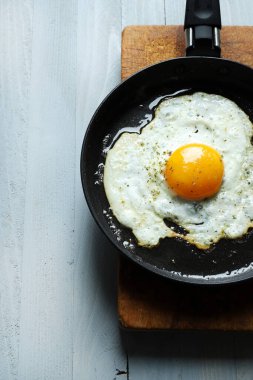 Gri arka planda kızartma tavasında tek bir yumurta. Sağlıklı gıda konsepti. Tam üstte.