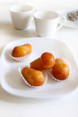 Lezzetli baba romu, tatlı alkollü tatlı mayalanmış hamuru roma batırılmış beyaz tabakta. Beyaz ahşap arkaplan, tam yukarıda, boşluğu kopyala.
