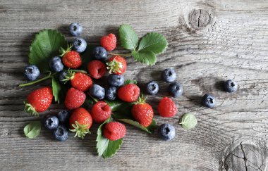 Taze meyveler. Ahşap bir arka planda izole edilmiş çilek, yaban mersini ve ahududu. Sağlıklı yiyecekler. Tam üstte.