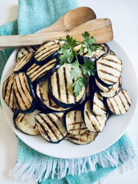 Masadaki beyaz tabakta ızgara patlıcan. Sağlıklı ve vejetaryen yemekleri. Tam üstte.