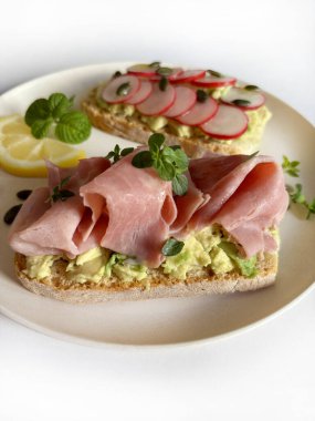 Prosciutto, turp, şifalı ot ve limonlu leziz avokado tostu. Sağlıklı yiyecekler. Tam üstte.