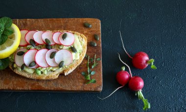 Arkaplanda turplu, otlu ve limonlu avokado tostu. Sağlıklı yiyecekler. Tam üstte.