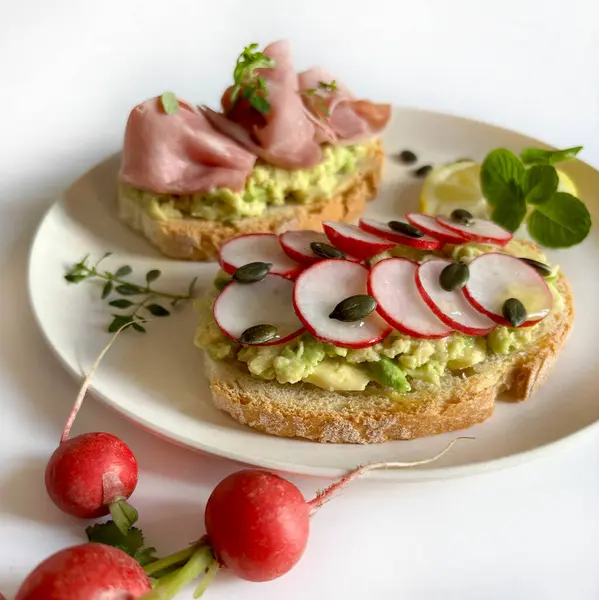 Prosciutto, turp, şifalı ot ve limonlu leziz avokado tostu. Sağlıklı yiyecekler. Tam üstte.