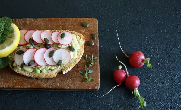 Arkaplanda turplu, otlu ve limonlu avokado tostu. Sağlıklı yiyecekler. Tam üstte.