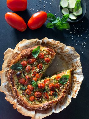 Kabaklı tatlı börek, kiraz domatesli yumurta ve siyah arka planda taze fesleğen yaprağı. Sağlıklı ve vejetaryen yemekleri. Tam üstte.
