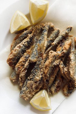 Beyaz tabakta kızarmış sardalya ve limon. Sağlıklı Akdeniz mezeleri. Deniz ürünleri konsepti.