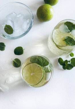 Hugo Spritz kokteyl içeceği. Beyaz ahşap bir masada köpüklü şarap, limon, nane yaprağı ve buz. Yaz kokteyli konsepti.