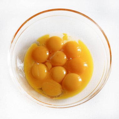 Beyaz bir masada cam kasede yumurta sarısı. Para kazanmak için yumurta sarısı. Yumurta sarısı yemek için. Tam üstte.