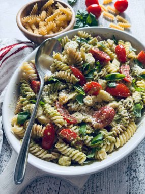 Taze kiraz domatesli pesto makarna salatası ve taze fesleğen yapraklarıyla süslenmiş mozzarella. İtalyan yaz yemeği. Sağlıklı gıda konsepti.