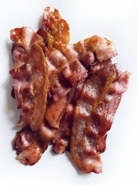 Beyaz arka planda izole edilmiş kızarmış pastırma dilimleri. Lezzetli kızarmış pastırma. Tam üstte.