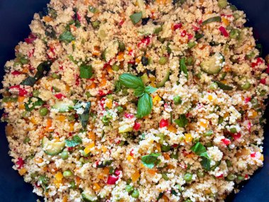 Havuç, kabak, biber ve taze fesleğen gibi pişmiş sebzelerle kuskus. Vejetaryen salatası. Sağlıklı ve vejetaryen yemekleri. Tam üstte.