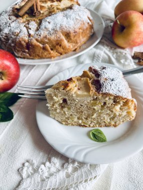Masanın arkasında tarçın çubukları ve taze elmalarla süslenmiş yumuşak ve lezzetli ev yapımı elmalı turta. Tam üstte.