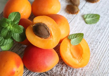 Tahta bir arka planda izole edilmiş taze nane yapraklarıyla dekore edilmiş bir grup taze kayısı. Yaz meyvesi. Sağlıklı yiyecekler. Tam üstte.