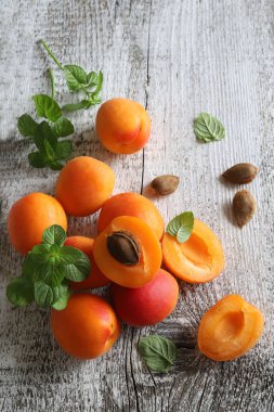 Tahta bir arka planda izole edilmiş taze nane yapraklarıyla dekore edilmiş bir grup taze kayısı. Yaz meyvesi. Sağlıklı yiyecekler. Tam üstte.