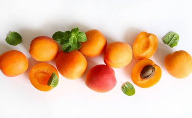 Beyaz arka planda izole edilmiş taze nane yapraklarıyla dekore edilmiş bir grup taze kayısı. Yaz meyvesi. Sağlıklı yiyecekler. Tam üstte.