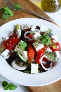 Beyaz peynirli Yunan salatası ve domates, biber, salatalık, soğan, zeytin ve ahşap masadaki kekik gibi taze sebzeler. Sağlıklı ve vejetaryen yemekleri.