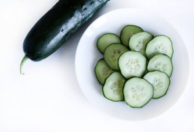 Beyaz arka planda tam ve dilimlenmiş salatalık. Salata malzemesi. Sağlıklı beslenme. Tam üstte.