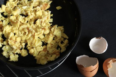 Siyah arka planda baharat ve otlarla çırpılmış yumurta. Sağlıklı kahvaltı. Tam üstte.