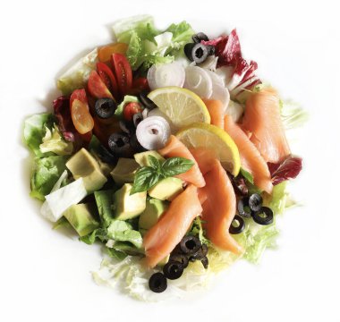 Somon füme salata, avokado, zeytin, limon, marul ve beyaz tabakta taze sebze. Sağlıklı yiyecekler. Tam üstte.