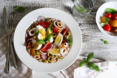 Haşlanmış yumurtalı ev yapımı salata, taze sebze ve ahşap arka planda fesleğen. Hecelenmiş salata. Sağlıklı yiyecekler. Tam üstte.