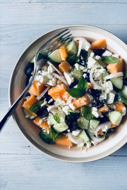 Lezzetli kavun, peynir, zeytin, salatalık aromalı salata ve gri ahşap arka planda taze fesleğen yaprağı. Hafif bir yaz yemeği..