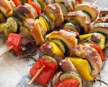 Et, sosis, sebze, otlar ve kağıt üzerinde ekmek dilimleriyle fırında pişirilmiş sade şişler. Genel bakış. Yakın plan..