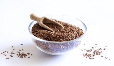 Beyaz arka planda izole edilmiş cam bir kasede keten tohumu. Keten tohumları lif, omega-3 yağ asitleri ve lingnan açısından zengindir. Sağlıklı gıda konsepti.