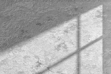 Güneş ışığından gelen doğal gölgeli beton desenli bir duvar çeşitli tasarımlarda kullanılabilen bir pencereden içeri giriyor..