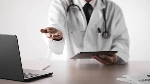 Hastane ofisindeki masada steteskoplu bir doktor. Sistematik sağlık yönetimi için bir doktora danışıyorum..